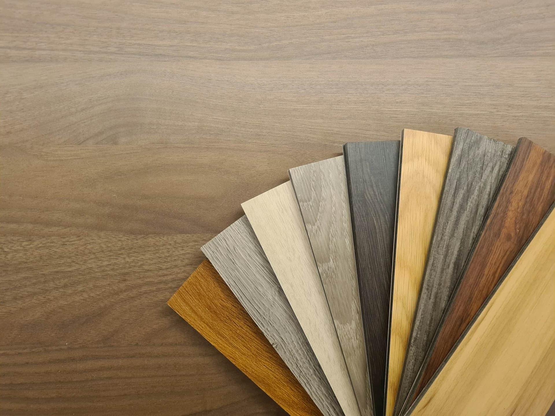 A fan of wood plank flooring samples in a range of tones