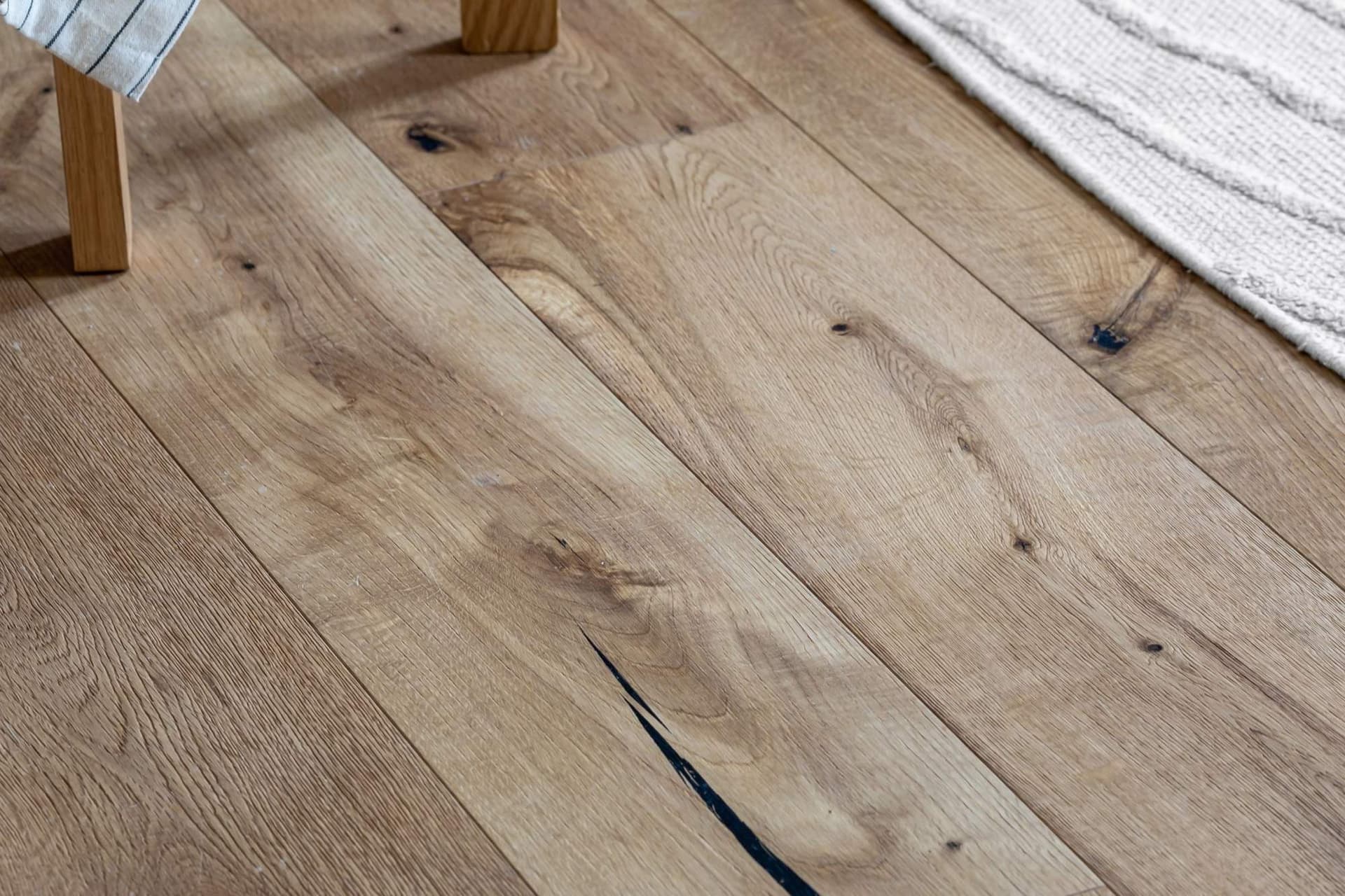 Close view of a wide oak plank floor in a furnished room