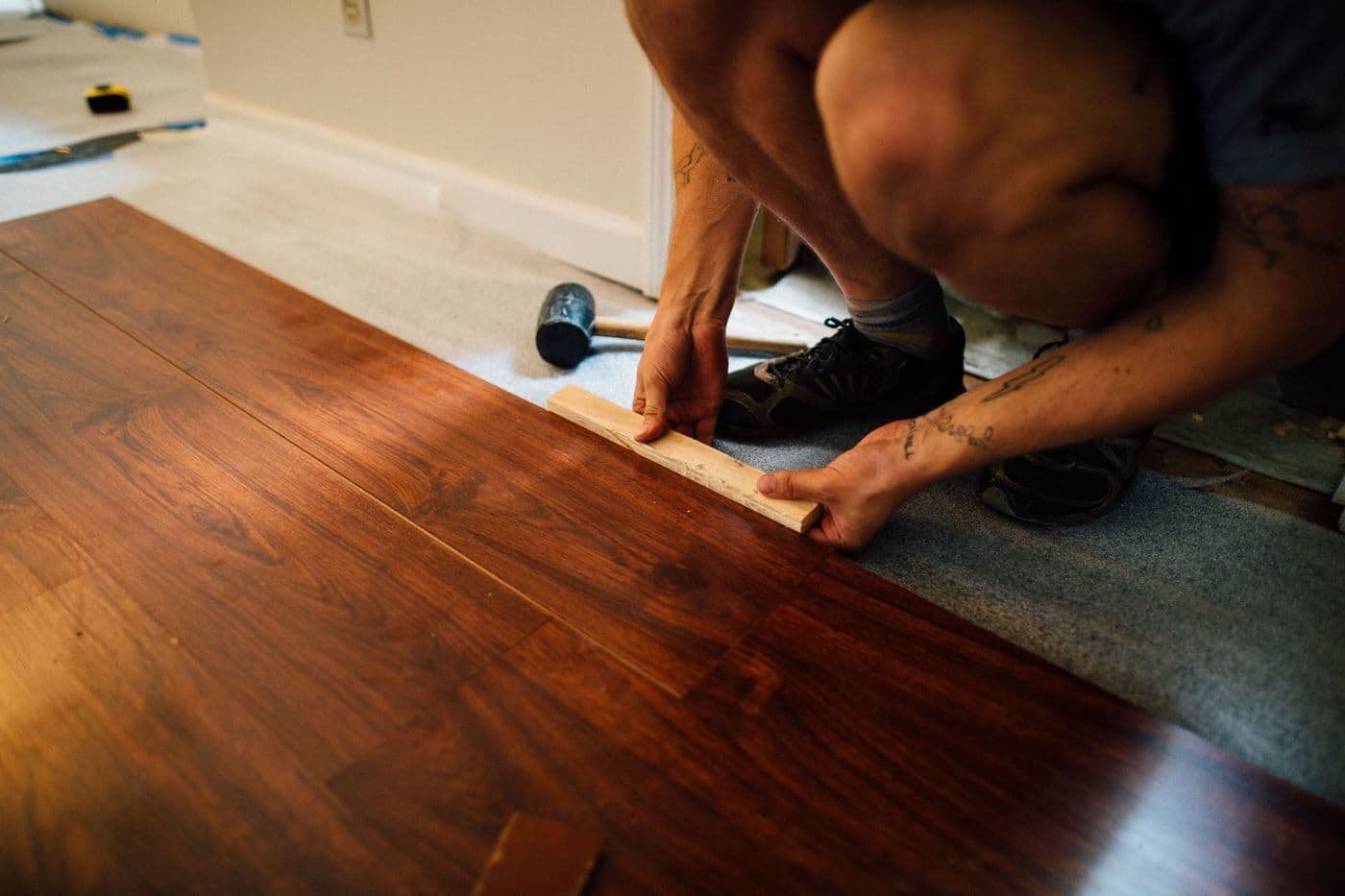 An installer fitting a laminate plank over underlayment